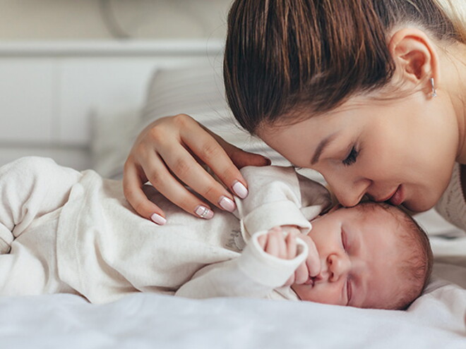 Świeżo upieczona mama po cesarskim cięciu leży na łóżku z noworodkiem